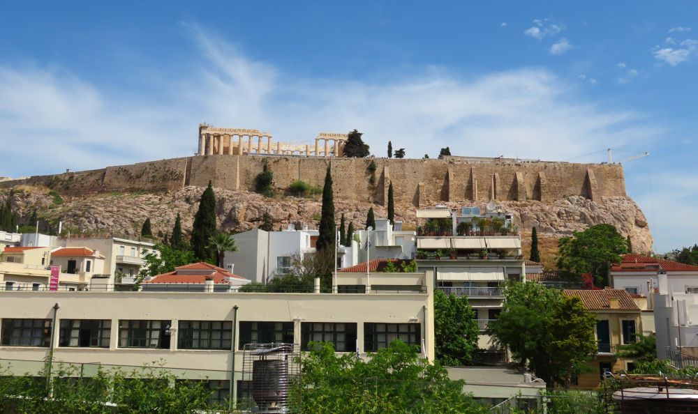 The Acropolis ruins on a rocky hill behind a mix of lower buildings.