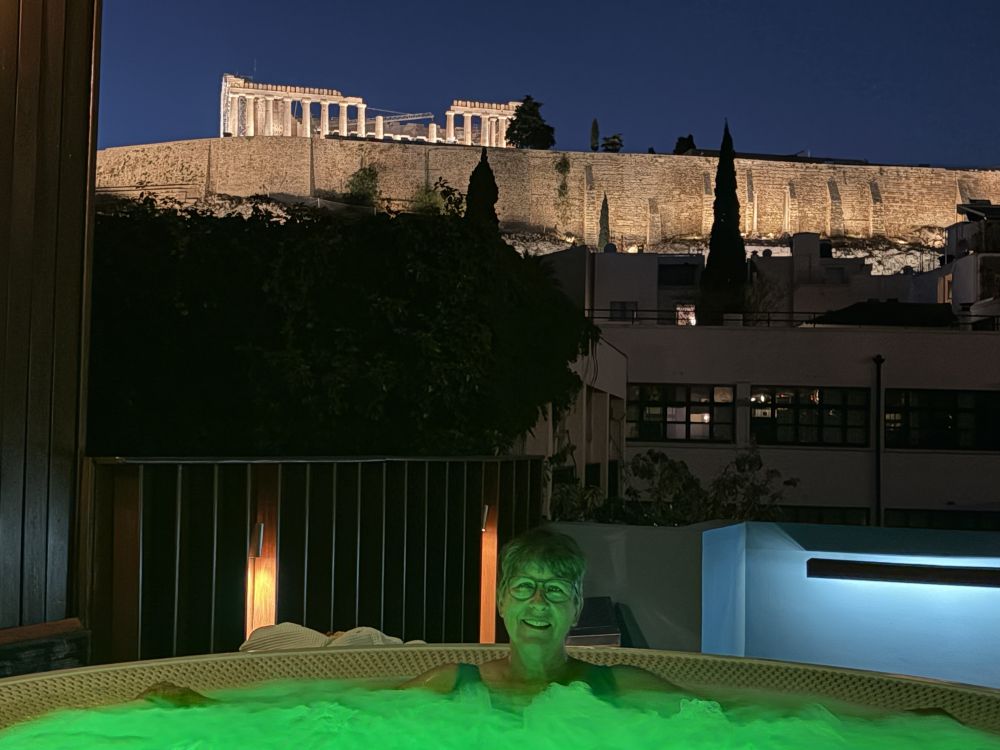 Me facing the camera from green-lit water, the Acropolis behind me, lit up.