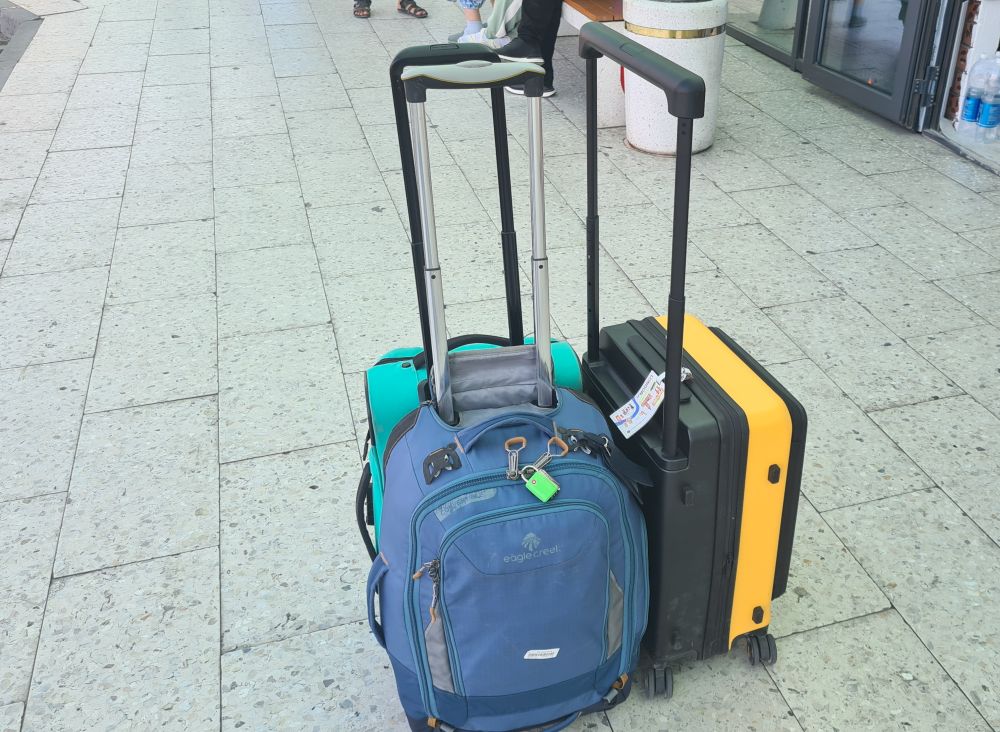 3 bags with handles extended: the Level8, a blue backpack-looking bag, and a green carry-on.