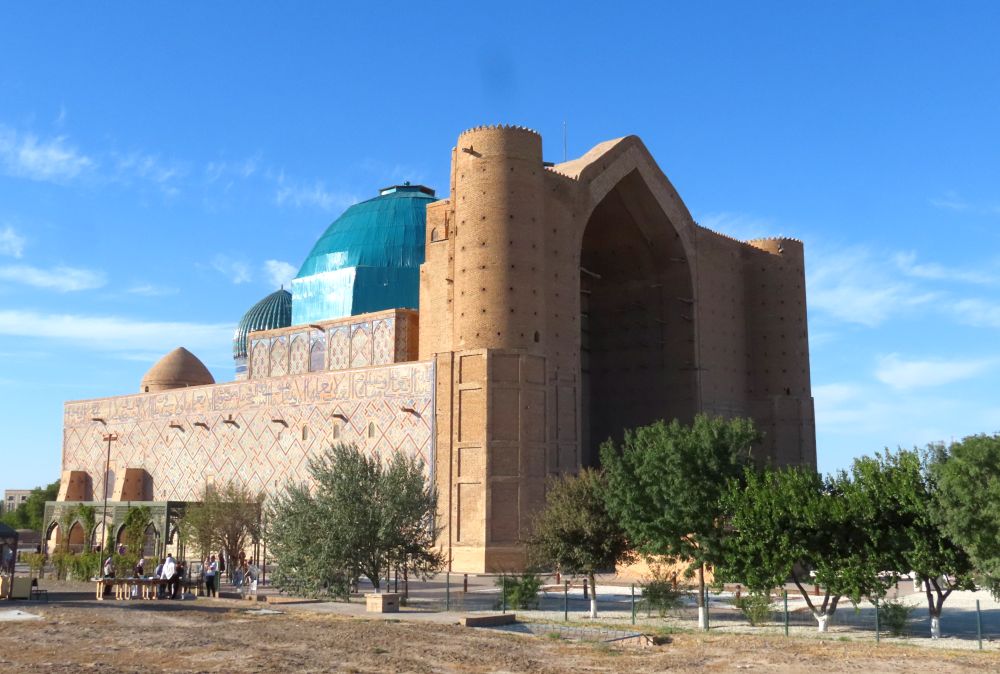 A very large brick building with a huge brick arch at the front and a blue dome in its center behind the arch.
