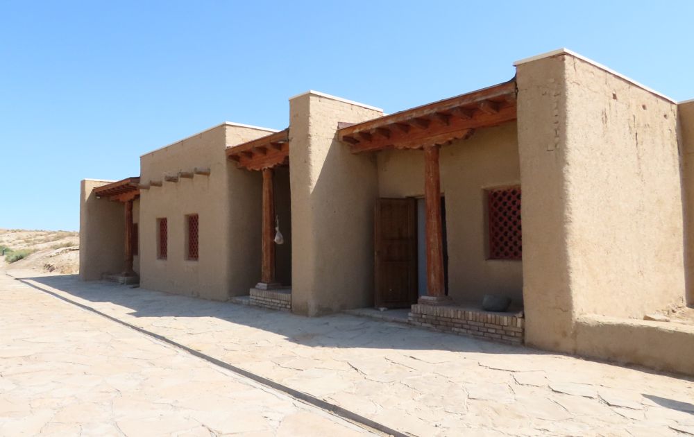 An adobe building, one story, with several entrances.